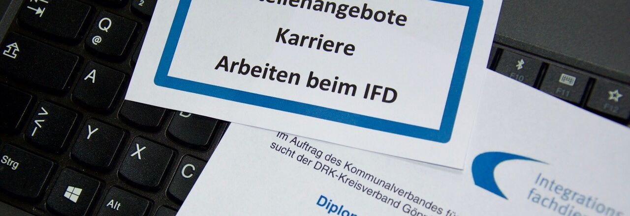 Muster eines Stellenangebotes liegt auf einer Computertastatur als Beispiel einer Bewerbung