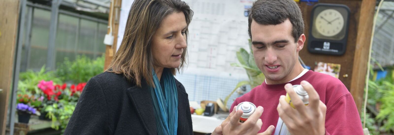 2 Mitarbeiter einer Gärtnerei die Hinweise auf Spraydosen lesen
